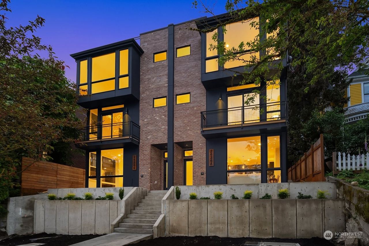 Three-story townhouse building with dark siding, large windows and two entrances
